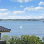 Wide view of the sea with sailboats and green landscape in the background.