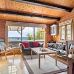 Living room with wooden walls, sofa, chair, and water view