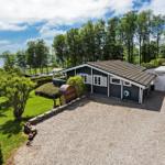 A house with a view of a lake, surrounded by lawns and trees.