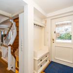 Eingangsbereich mit Garderobe und Tür. Treppenhaus und Wohnbereich sichtbar.