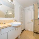 Badezimmer mit Dusche, Waschbecken und Spiegel.