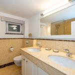 Badezimmer mit Doppelwaschbecken, Spiegel und Toilette.