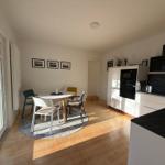 Küche mit Essbereich, Holzboden und Glastür zum Außenbereich.