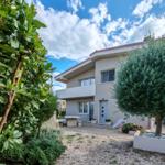 House with garden, terrace, and playground under blue sky.