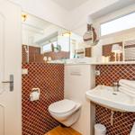 Badezimmer mit Toilette, Waschbecken und Badewanne. Wandfliesen mit Muster.