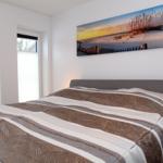 Schlafzimmer mit Bett, Wandbild und Nachttisch.