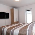 Schlafzimmer mit Bett, TV und Schränken an der Wand.
