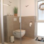 Bad mit Dusche, WC und Fenster mit Dekor.