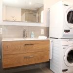 Badezimmer mit Waschmaschine und Trockner. Holzwaschtisch und Spiegel.