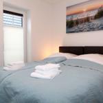 Schlafzimmer mit Bett, Decke und Fenster. Wandbild zeigt Strand bei Sonnenuntergang.