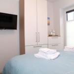 Schlafzimmer mit Bett, TV und Schränken. Fenster mit Jalousie.
