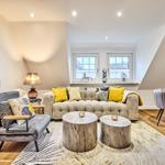 Wohn- und Essbereich mit Sofa, Sessel und Holztischen