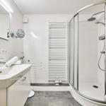 Badezimmer mit Dusche, Waschbecken und Heizkörper.