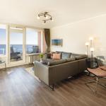 Wohnbereich mit Sofa, Esstisch und Meerblick über Balkon.