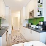 Küche mit weißen Schränken, grüner Rückwand und Küchenzeile