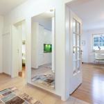 Eingangsbereich mit Blick in Küche und Esszimmer. Holzboden und weiße Wände.