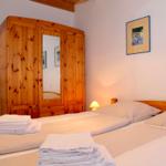 Schlafzimmer mit Holzbett, Kleiderständer und Kleiderschrank mit Spiegeltür.