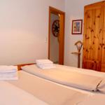 Schlafzimmer mit Bett, Holzschrank und Handtüchern.