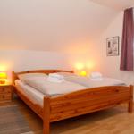 Ein Schlafzimmer mit Holzbett, Nachttischen und Fenster.