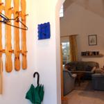 Eingangsbereich mit Holzgarderobe und Blick in das Wohnzimmer mit Sofa und Couch.