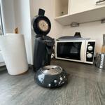 Küchenzeile mit Kaffeemaschine, Mikrowelle und Küchenutensilien.