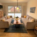 Wohnzimmer mit zwei Sofas, Holztisch und Fernseher an der Wand.