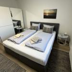 Schlafzimmer mit Doppelbett, Kleiderschrank und Wandbild.