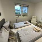 Zimmer mit Doppelbett, Fenster, Sessel und Wandbildern.
