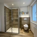 Badezimmer mit Dusche, Toilette und Fenster