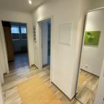 Flur mit Holzboden, Teppich und Spiegelschrank. Bilder an den Wänden.
