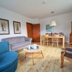 Wohn- und Essbereich mit Holzboden, Sofa, Stühlen und Tisch.