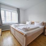 Schlafzimmer mit Holzbett, Fenster und Nachttisch.