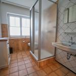 Badezimmer mit Dusche, Waschbecken und Fenster.