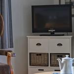 Ein Fernseher auf einem weißen Schrank mit Körben und einem Stuhl im Hintergrund.