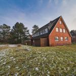 Rotes Backsteingebäude mit Dachgarage und schneebedecktem Grundstück.