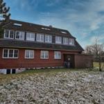 Zweistöckiges Haus mit Schneebedecktem Grundstück und Holzveranda.