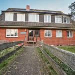 Rotes Backsteingebäude mit Holztor und Schriftzug Haus Pax.