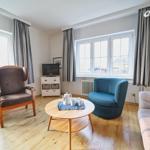 Wohnzimmer mit Sitzgelegenheiten, Tisch und Fenstern.