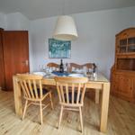 Esszimmer mit Holztisch, Stühlen und Sideboard. Hängelampe und Wandbild sichtbar.