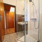 Badezimmer mit Dusche, Waschbecken und Mosaikfußboden.