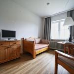 Ein Raum mit Holzmöbeln, Fernseher, Sofa und Tisch mit Stühlen.