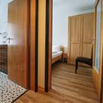 Schlafzimmer mit Bett, Kleiderschrank und Stuhl. Flur mit Holzboden und Mosaikfliesen.