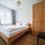 Schlafzimmer mit Holzbett, Kleiderschrank und Fenster mit Vorhängen.