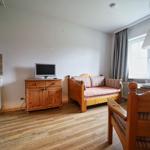 Wohn- und Essbereich mit Holzmöbeln, Fernseher und Küchenzeile.