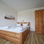 Ein Schlafzimmer mit Holzbett, Kleiderschrank und Wandbild.