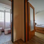 Schlafzimmer mit Holzbett und angrenzender Badewanne mit Toilette.