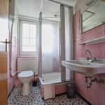 Badezimmer mit Dusche, Waschbecken und Toilette. Wände rosa gefliest.