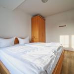 Schlafzimmer mit Doppelbett, Kleiderschrank und Holzboden.