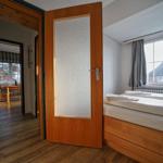 Schlafzimmer mit Bett, Fenster und Tür zur Küche.