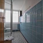 Badezimmer mit blauen Fliesen, Mosaikboden und Fenster mit Jalousie.